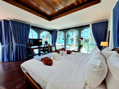 a bedroom with a large white bed with blue curtains at Solstice Phuket in Nai Thon Beach