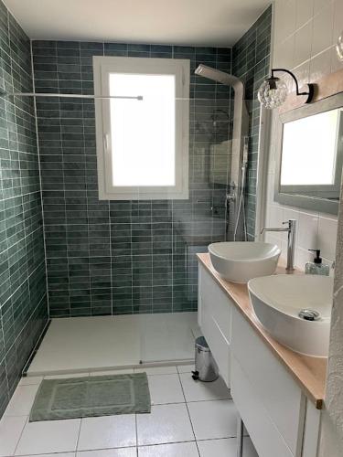 La salle de bains est pourvue de 2 lavabos et d'une douche avec une fenêtre. dans l'établissement Maison familiale, à Saint-Cyr