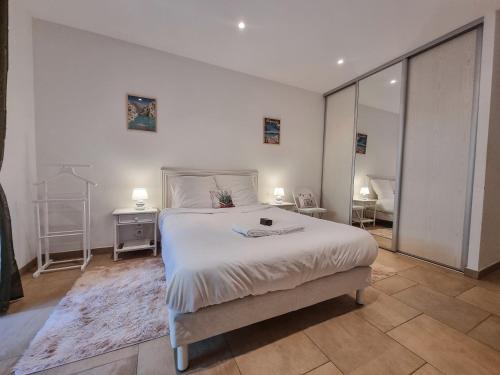 une chambre blanche avec un lit et un miroir dans l'établissement Le Jardin d'Été à la Mer - T2 avec jardin, clim, parking, à Cavalaire-sur-Mer