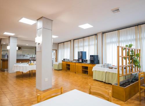 a large room with tables and chairs and a kitchen at Hotel Alda Boiro in Boiro