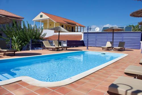 a swimming pool with chairs and a house at Kekatos Studios in Lassi