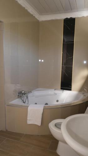 a bathroom with a tub and a toilet and a sink at Thandi's Guest House in East London