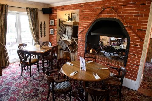 a restaurant with two tables and a brick fireplace at The Mortimer Arms in Romsey