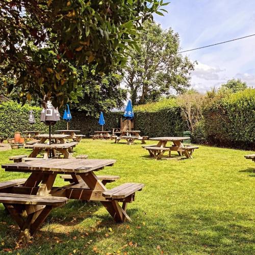 a group of picnic tables in the grass with blue umbrellas at The Mortimer Arms in Romsey