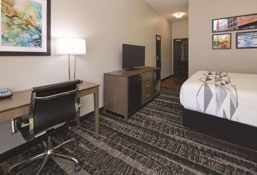 a hotel room with a bed and a desk and a computer at La Quinta by Wyndham Tyler South in Tyler