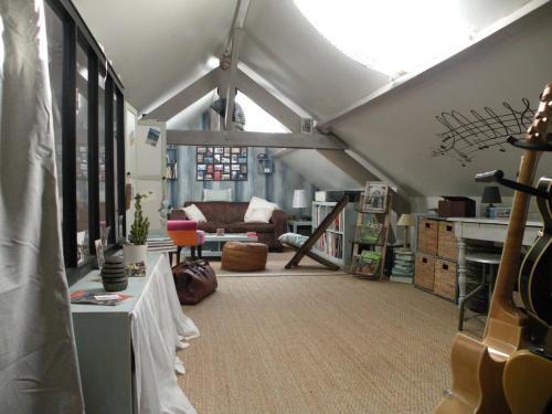 a attic room with a couch and a guitar at Chambre cooconing salon avec canape convertible in Déville-lès-Rouen