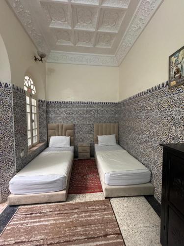 two beds in a room with two windows at Riad Blue Garden in Rabat