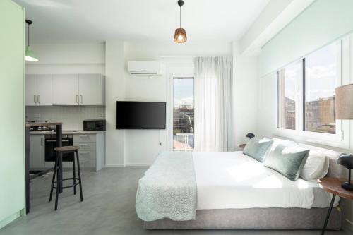 a white bedroom with a bed and a kitchen at Revived Studio - Urban Charm in Athens