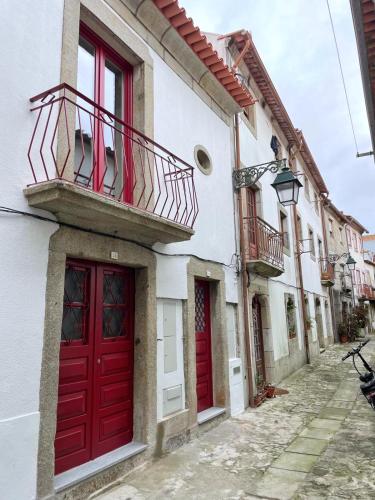 a building with red doors and a balcony at CasAmalia 54 in Viana do Castelo