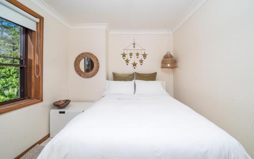 a white bedroom with a large bed and a window at Point Clare - Relax and unwind - Greenery & Birdsongs in Point Clare