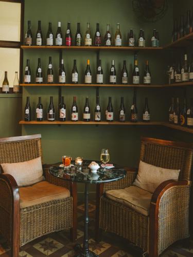 a room with two chairs and a table and shelves of wine bottles at Le Saint Hubert in Saint-Saturnin-les-Apt