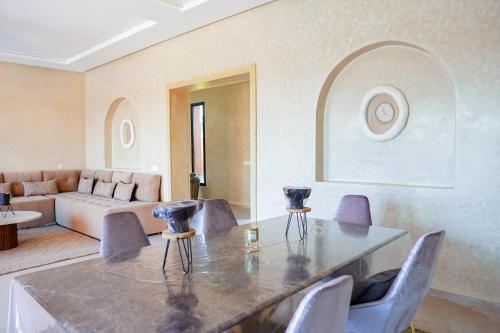 a living room with a table and chairs and a couch at VILLA NOÛR PALACE avec piscine jaccuzi à Marrakech in Marrakech