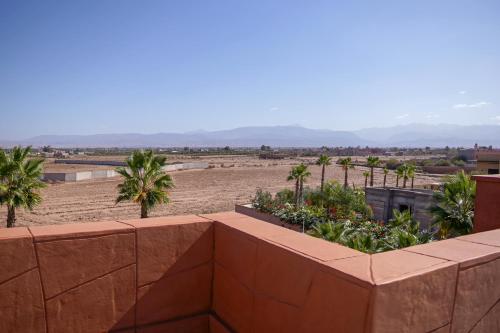 a view of a desert with palm trees and a retaining wall at VILLA NOÛR PALACE avec piscine jaccuzi à Marrakech in Marrakech