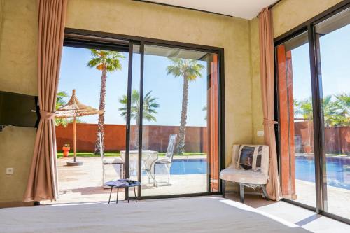 a living room with sliding glass doors and palm trees at VILLA NOÛR PALACE avec piscine jaccuzi à Marrakech in Marrakech