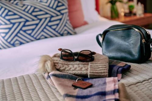 a pair of glasses and a purse on a bed at The Stag on the River in Godalming