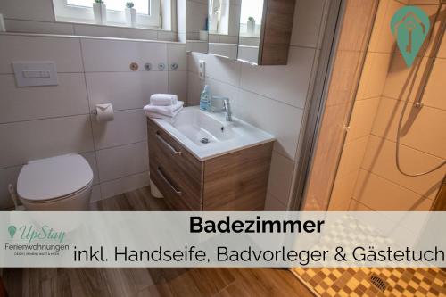 a bathroom with a sink and a toilet and a mirror at Butzenhuuske in Krummhörn