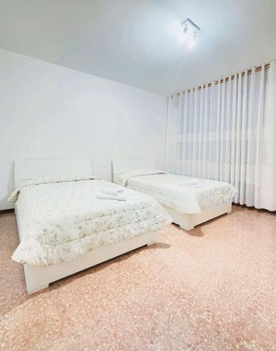 two beds in a room with white walls at Casablanca in Venice