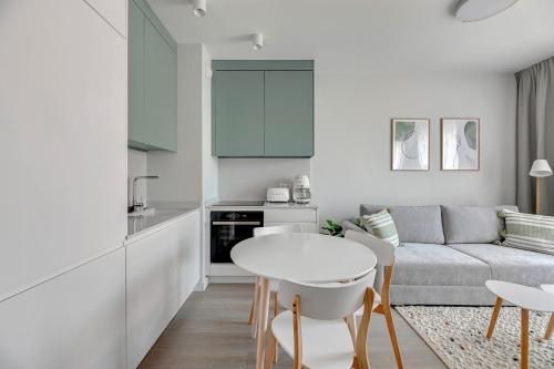 a white living room with a table and a couch at Scala Apartamenty by Moderna Profit- Łąkowa 60C in Gdańsk