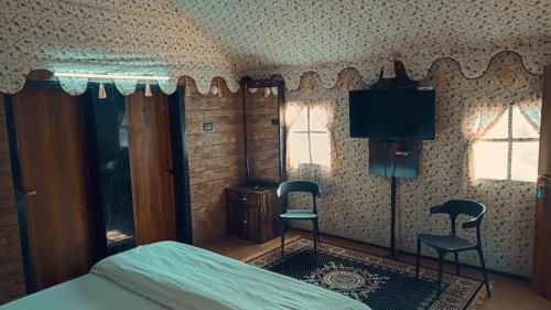a bedroom with a bed and two chairs and a tv at The Royal River Resort in Keonchi