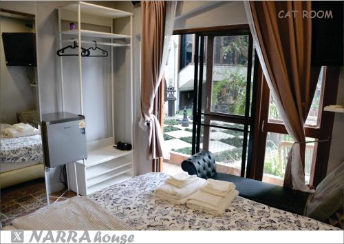 a bedroom with a bed and a large window at Narra House Sukhumvit58 in Bangkok