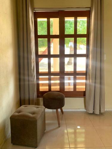 a chair and a stool in front of a window at Casadijaina in Amontada