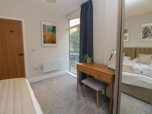 a bedroom with a desk and a bed and a window at 2 Rock Mill Holiday Apartments in Eyam