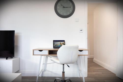 a desk with a white chair and a clock on a wall at Hatfield Haven - Modern 2-Bed Retreat near Uni, Business Park & City Center, FREE Parking, Big savings on Longer Stays in Hatfield