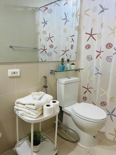 a bathroom with a toilet and a shower curtain at Beach Vibe Condo with PS4, Mini Karaoke, Board Games in Azure North San Fernando Pampanga in San Fernando