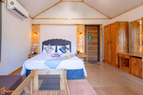 Un dormitorio con una cama grande y suelo de madera. en Natures Dreamland Holiday Homes, Igatpuri, en Igatpuri