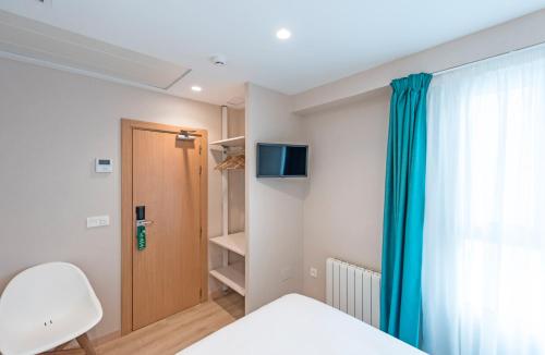 a bedroom with a bed and a window and a chair at La Lonja in Alicante