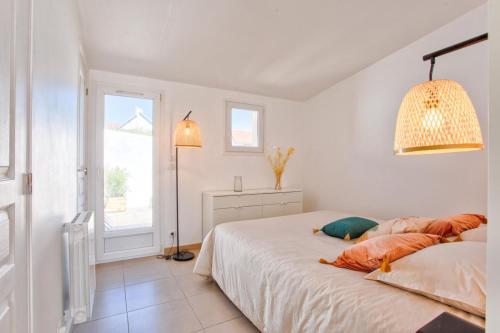 a white bedroom with a bed and a window at L'atypique, avec terrasse à 150M de la plage in Lion-sur-Mer