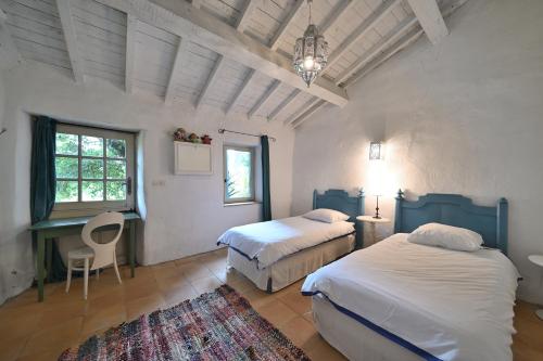 a bedroom with two beds and a desk and a window at La Maison D'amis Du Chateau in Pech-Luna