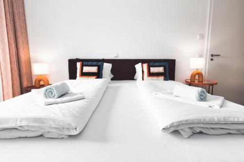 two beds in a room with white sheets and pillows at HEIMATEL - Bodensee Residenz Allgäu in Scheidegg