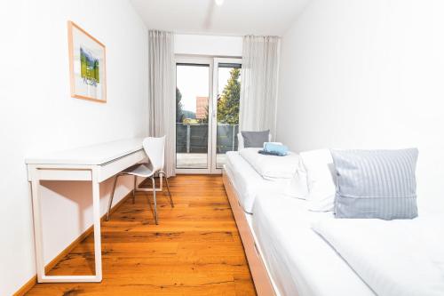 a white bedroom with a desk and a white couch at HEIMATEL - Bodensee Residenz Allgäu in Scheidegg