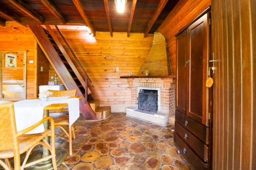 a room with a fireplace and a table and chairs at VELINN Hotel Fazenda Fonte das Hortênsias in Santo Antônio do Pinhal