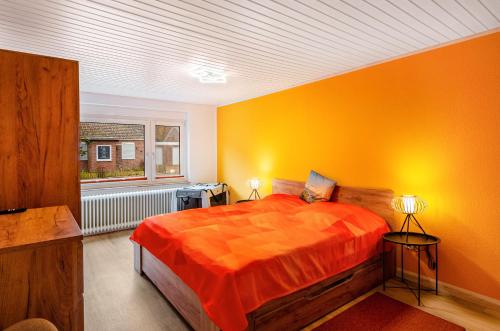 a bedroom with orange walls and a bed and a window at Perle von Berumbur in Berumbur