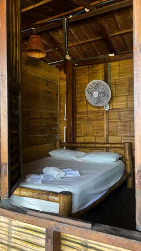 a bed in a wooden room with a fan at Hostal halaliku tayrona in Santa Marta