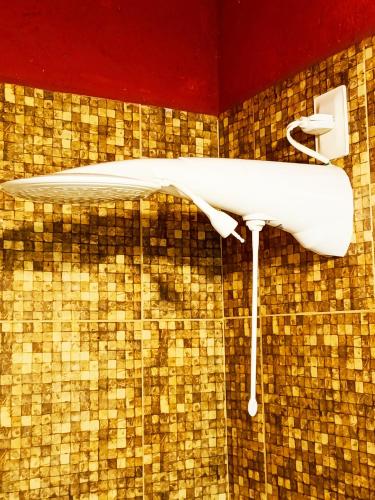 a shower in a bathroom with a brown tiled wall at Pipa Om in Pipa