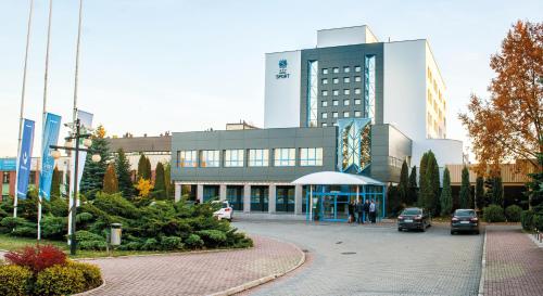 a large building with cars parked in front of it at Hotel Sport in Bełchatów