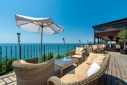a patio with wicker furniture and an umbrella at Kaliakria Resort in Topola