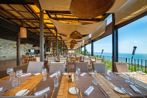 a restaurant with tables and chairs with the ocean in the background at Kaliakria Resort in Topola