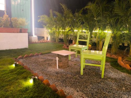 two chairs and a table in a garden at night at Cozy Cottage near Hessarghatta in Bengaluru