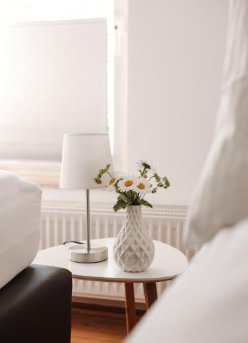 a vase of flowers on a table next to a bed at Freistehendes 4-Sterne Ferienhaus in der Uckermark in Haßleben