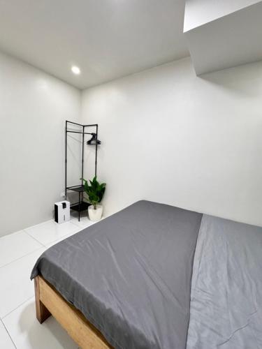 a white bedroom with a bed with a gray blanket at KM Suites 2BR Unit Near San Juan LU in San Fernando