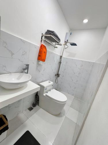 a white bathroom with a toilet and a sink at KM Suites 2BR Unit Near San Juan LU in San Fernando