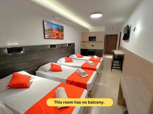 a room with four beds with orange pillows at Bayside A Apartments in St Julian's