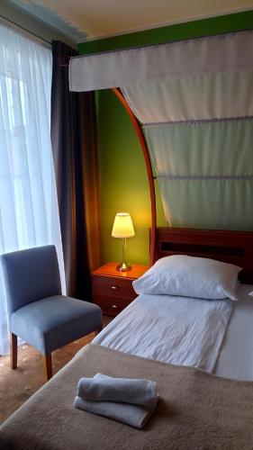 a bedroom with a bed and a chair and a lamp at Willa Akacja in Gdynia