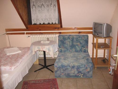 タタにあるHattyú Fogadóのテーブル、椅子、テレビが備わる客室です。