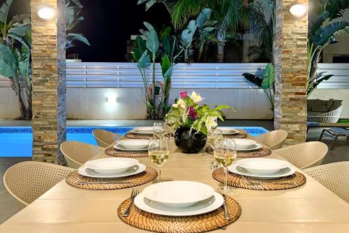 a table with white plates and glasses of wine at Villa Anastasia - Fig Tree Bay Area in Protaras