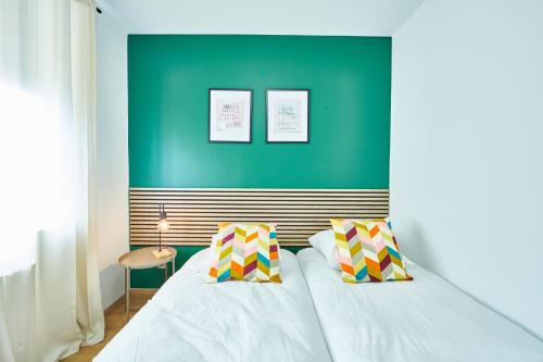 une chambre avec un lit blanc avec un mur vert dans l'établissement BE-2G - Appartement F2 pour 1-2 pers au 2ème étage au centre de Mulhouse, à Mulhouse